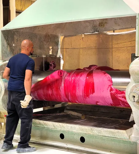 An operator working a batch of red rubber on an open mill at the Graphic Arts Rubber plant